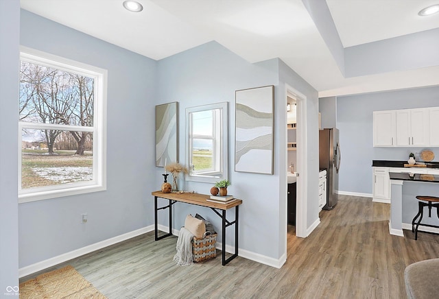 interior space with white cabinetry, stainless steel fridge, and light hardwood / wood-style floors