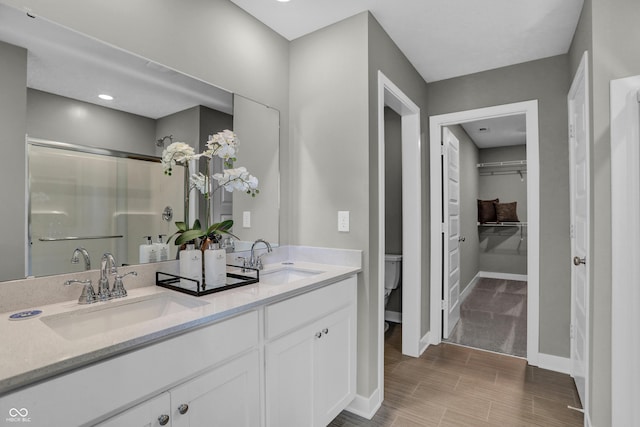 bathroom with vanity, toilet, and a shower with door