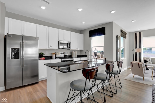 kitchen with a breakfast bar area, sink, appliances with stainless steel finishes, and an island with sink