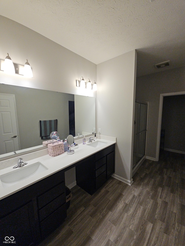 bathroom with a shower with door, vanity, a textured ceiling, and hardwood / wood-style flooring