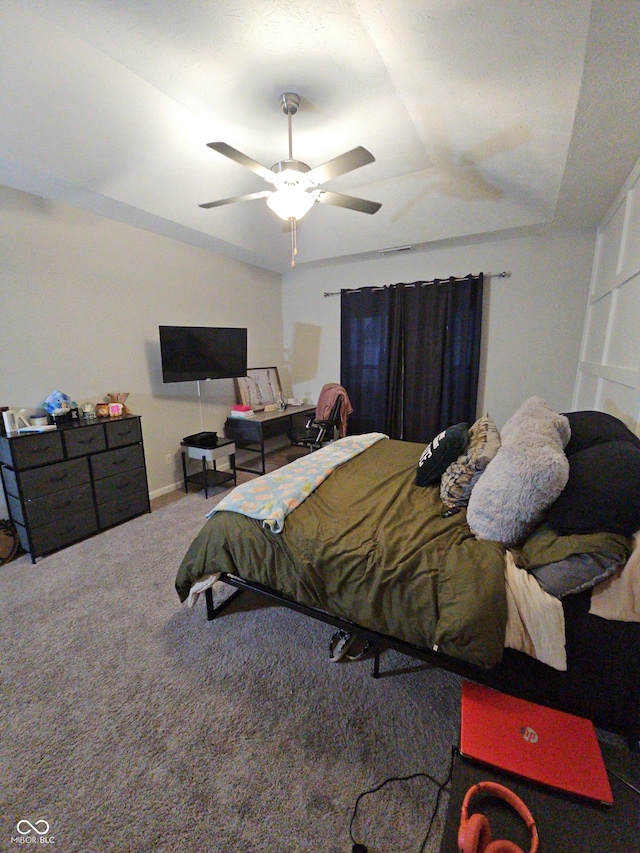 bedroom featuring carpet floors, a raised ceiling, and ceiling fan