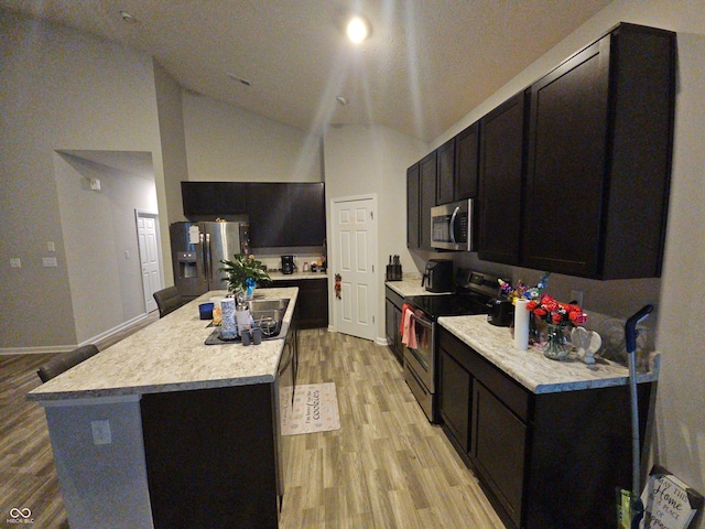 kitchen featuring a center island, high vaulted ceiling, stainless steel appliances, and light hardwood / wood-style flooring