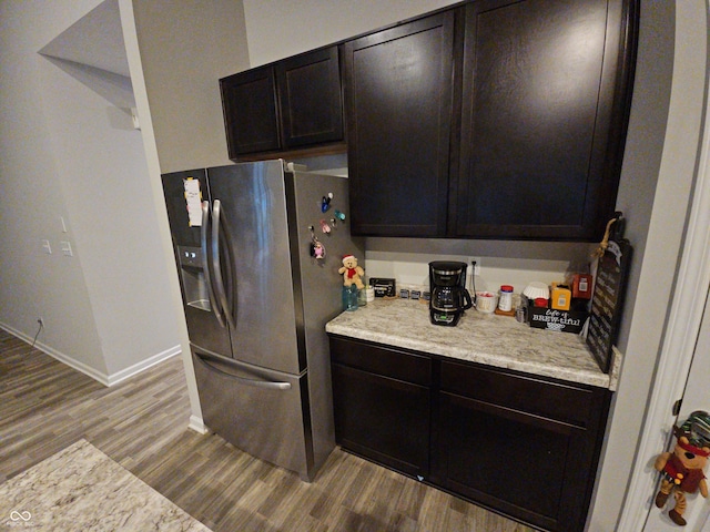 kitchen with dark brown cabinetry, light hardwood / wood-style floors, and stainless steel refrigerator with ice dispenser