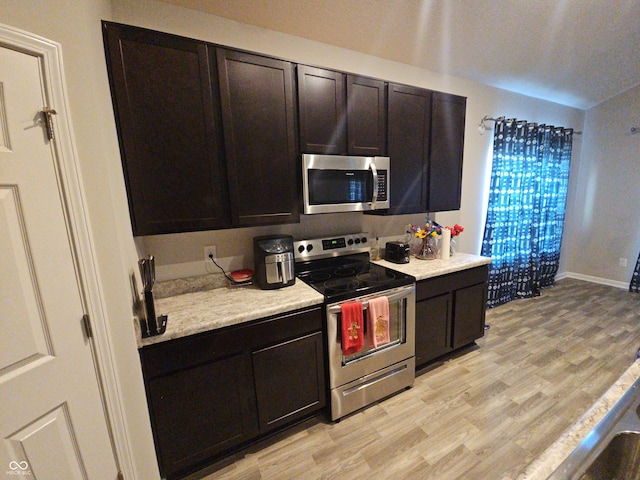 kitchen featuring light hardwood / wood-style floors, light stone counters, dark brown cabinetry, and stainless steel appliances