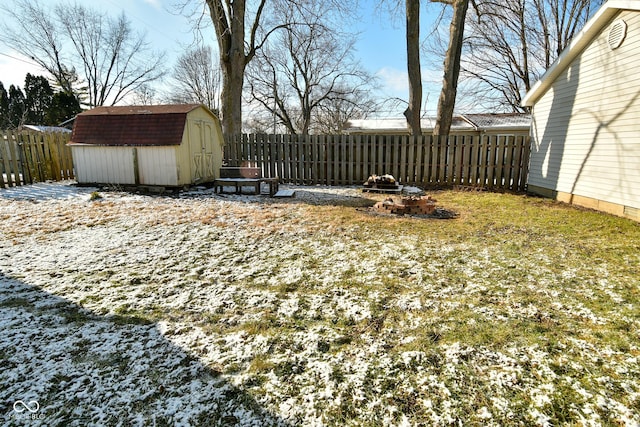 yard covered in snow with an outdoor fire pit and a storage unit