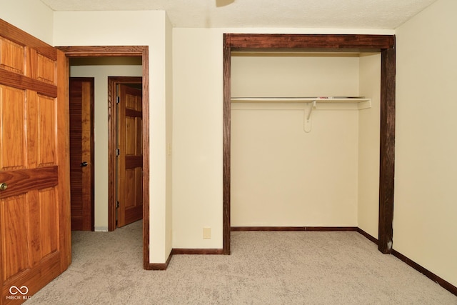 unfurnished bedroom with light colored carpet, a closet, and a textured ceiling