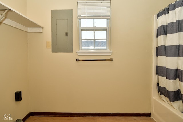 interior space featuring hardwood / wood-style flooring, electric panel, and shower / tub combo with curtain