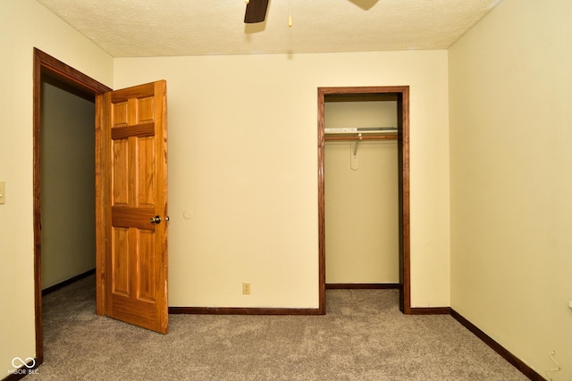 unfurnished bedroom featuring ceiling fan, light colored carpet, a textured ceiling, and a closet