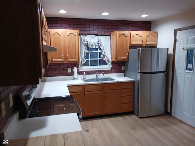 kitchen featuring stainless steel appliances, tasteful backsplash, sink, and light wood-type flooring