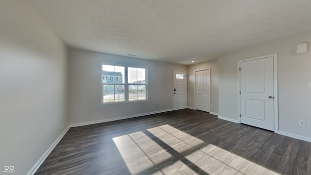 empty room featuring a textured ceiling and dark hardwood / wood-style floors