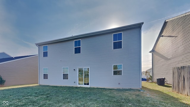 back of house featuring central AC unit and a lawn