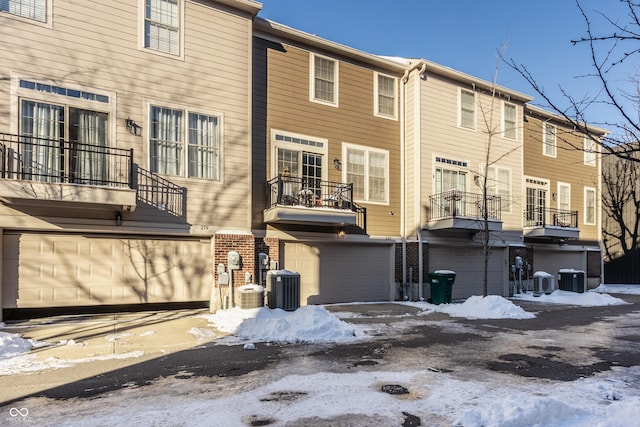 snow covered rear of property featuring central AC