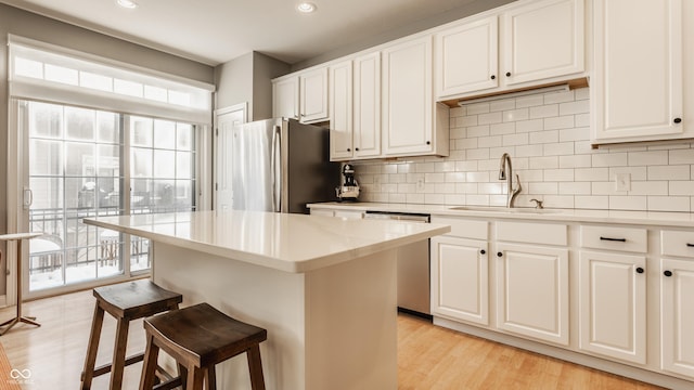 kitchen with white cabinets, a kitchen breakfast bar, sink, a kitchen island, and stainless steel appliances