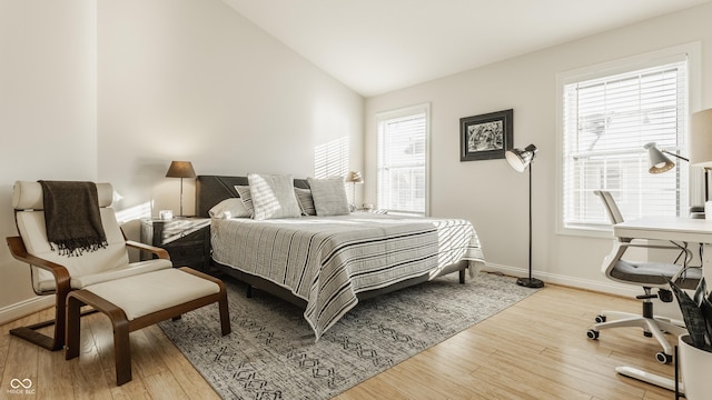 bedroom featuring multiple windows, lofted ceiling, and light wood-type flooring