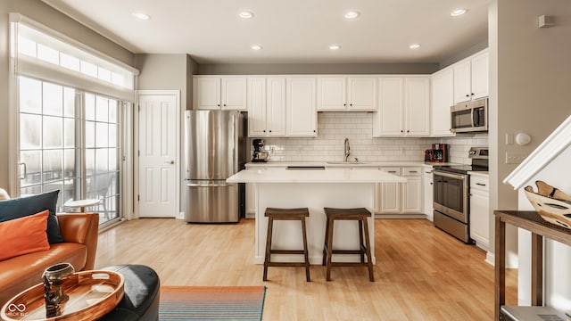 kitchen with white cabinetry, sink, a center island, stainless steel appliances, and light hardwood / wood-style flooring