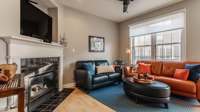 living room with ceiling fan, dark wood-type flooring, and a tiled fireplace