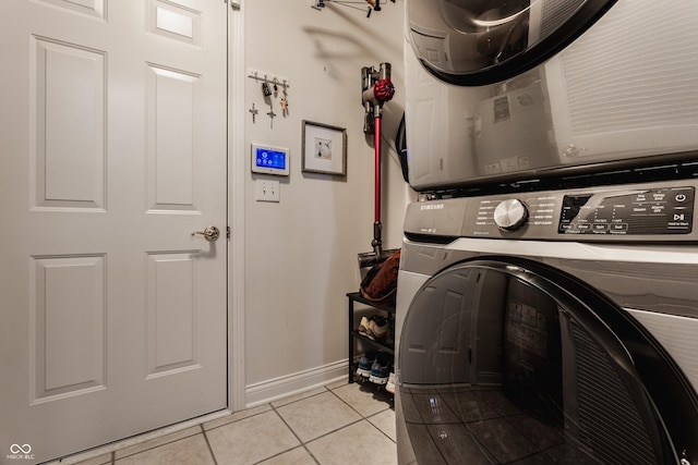 laundry area with stacked washer / dryer and light tile patterned flooring