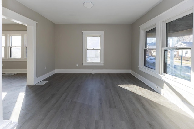 empty room featuring dark hardwood / wood-style flooring and a wealth of natural light