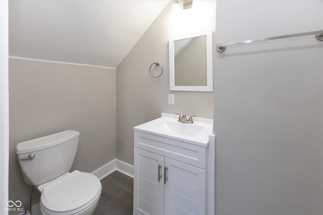 bathroom featuring hardwood / wood-style flooring, vanity, lofted ceiling, and toilet