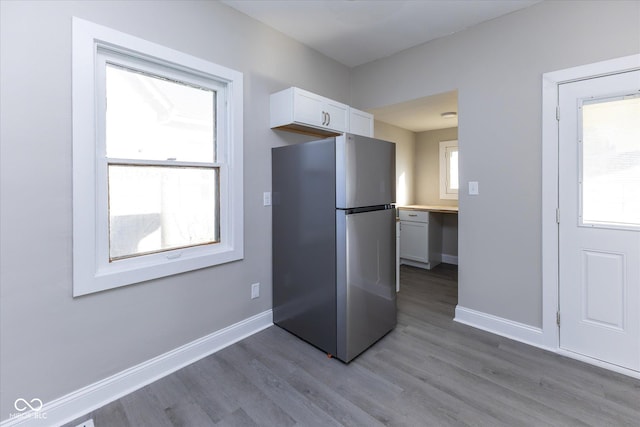 kitchen with butcher block countertops, stainless steel fridge, white cabinets, and light wood-type flooring