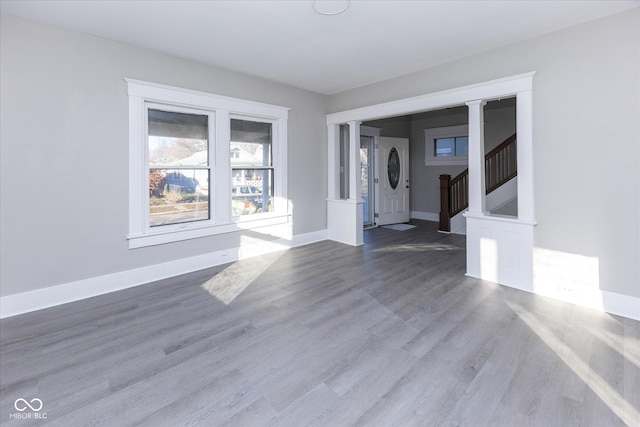 empty room with ornate columns and light hardwood / wood-style floors