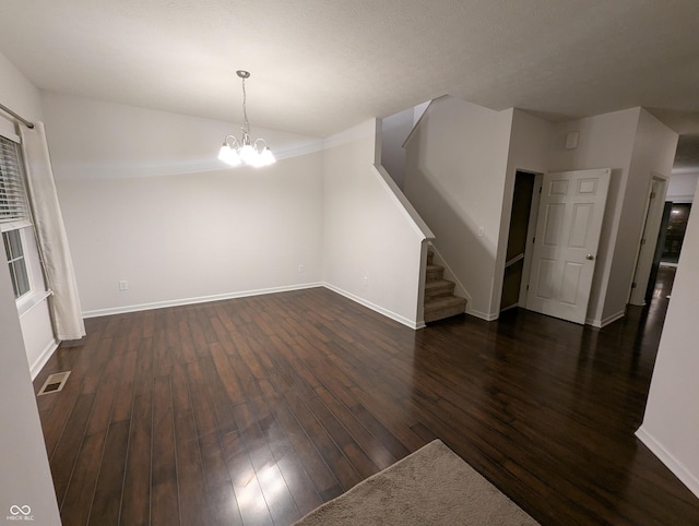 unfurnished living room featuring dark hardwood / wood-style flooring and an inviting chandelier