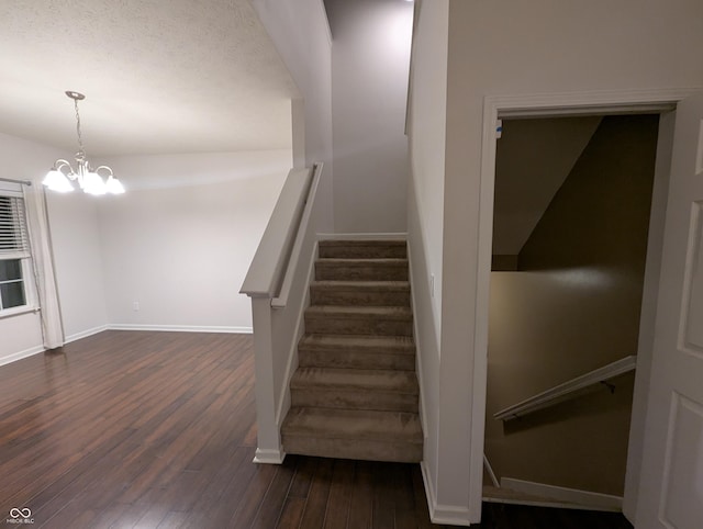 staircase with hardwood / wood-style floors and a chandelier