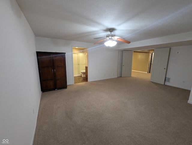 unfurnished bedroom featuring light carpet, connected bathroom, and ceiling fan