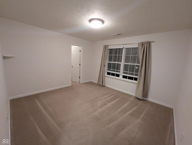 carpeted empty room featuring a textured ceiling