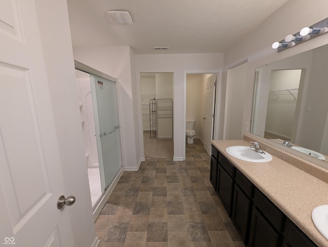 bathroom featuring vanity, toilet, and a shower with shower door