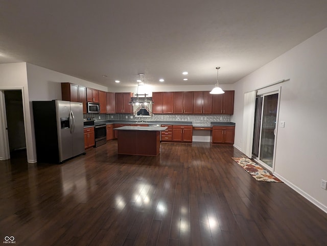 kitchen with sink, decorative backsplash, hanging light fixtures, a center island, and stainless steel appliances