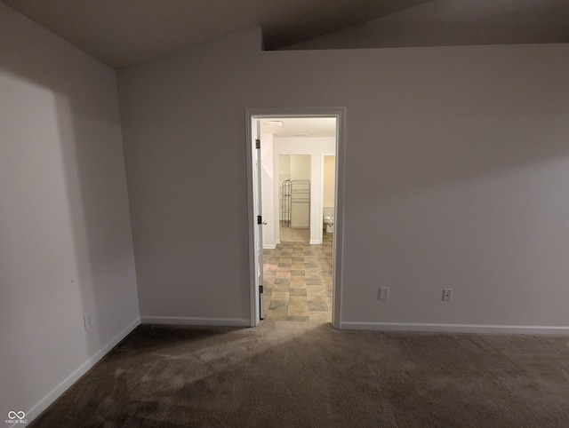 carpeted empty room with vaulted ceiling