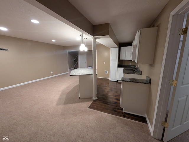 kitchen featuring sink, hanging light fixtures, white cabinets, a kitchen bar, and dark carpet