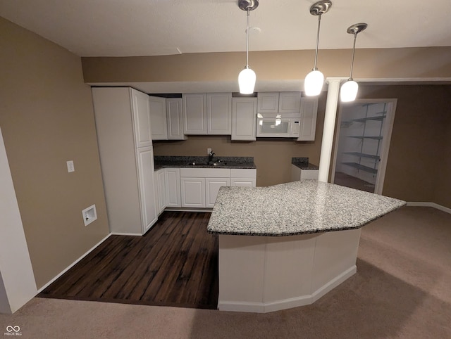 kitchen featuring sink, hanging light fixtures, and white cabinets