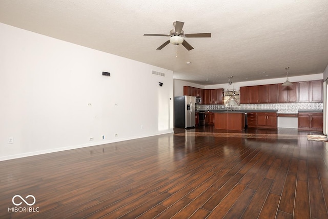 unfurnished living room with dark wood-style floors, visible vents, a sink, ceiling fan, and baseboards