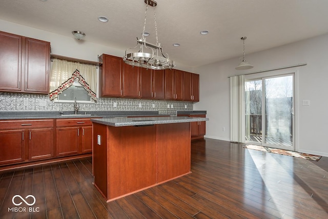 kitchen with a kitchen island, a sink, decorative backsplash, dark wood-style floors, and decorative light fixtures