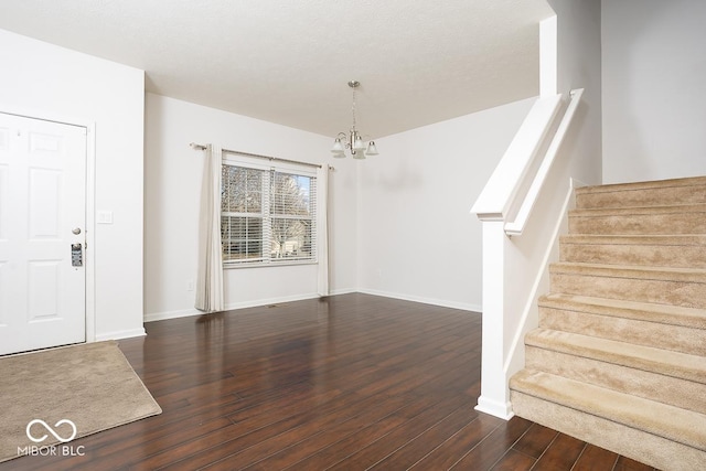 entryway featuring stairs, hardwood / wood-style floors, baseboards, and an inviting chandelier