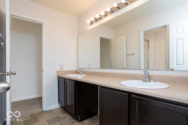 full bathroom with a sink, baseboards, and double vanity