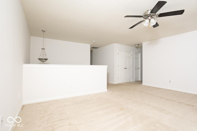 spare room with baseboards, a ceiling fan, and light colored carpet