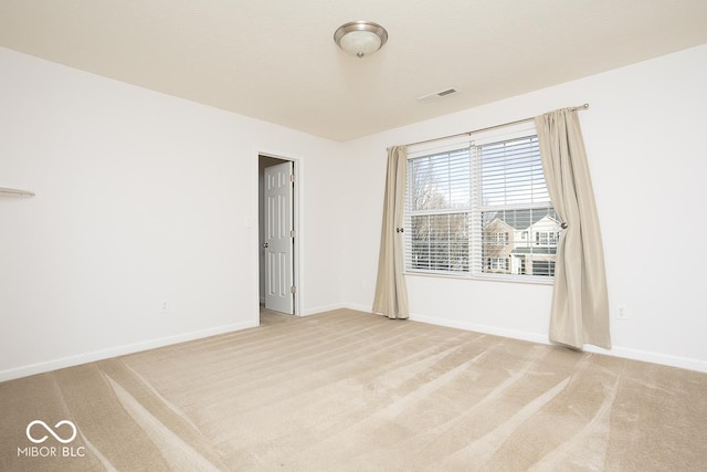 unfurnished room with baseboards, visible vents, and light colored carpet