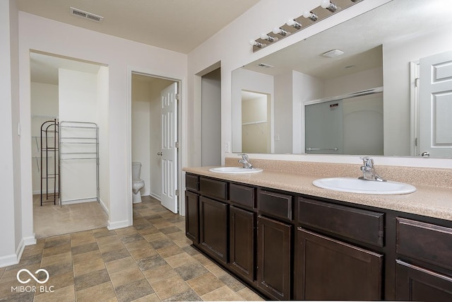 bathroom with visible vents, a sink, toilet, and double vanity