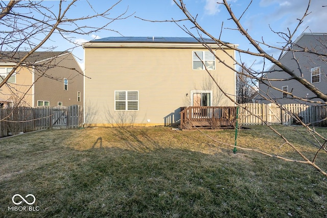 rear view of property featuring a fenced backyard, solar panels, and a yard