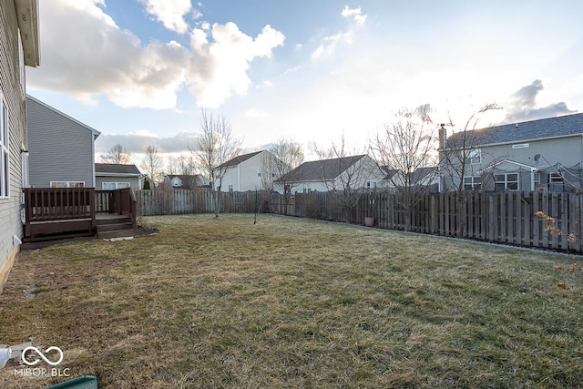 view of yard featuring a deck, a fenced backyard, and a residential view