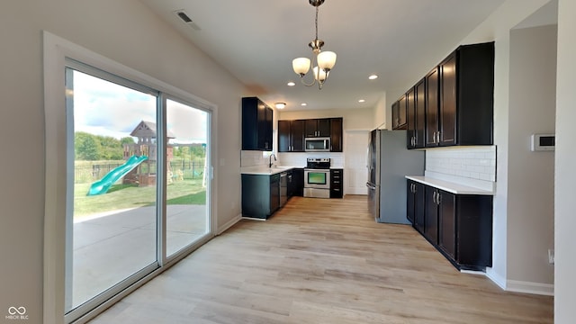 kitchen with light hardwood / wood-style flooring, a healthy amount of sunlight, stainless steel appliances, and tasteful backsplash