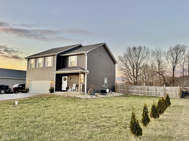 exterior space featuring a garage, driveway, a lawn, and fence