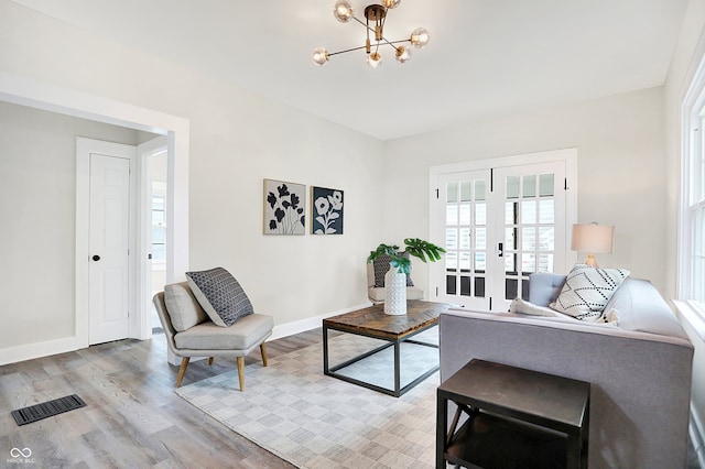 living room featuring hardwood / wood-style floors, french doors, and an inviting chandelier