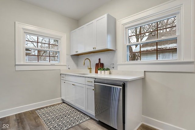 bar featuring dishwasher, white cabinets, light hardwood / wood-style flooring, and sink