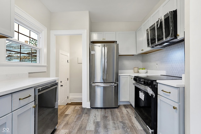 kitchen with white cabinets, backsplash, light hardwood / wood-style floors, and black appliances