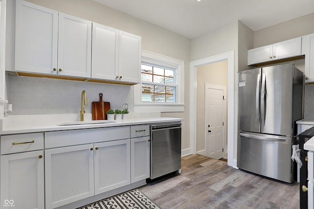 kitchen featuring sink, white cabinets, light hardwood / wood-style flooring, and appliances with stainless steel finishes