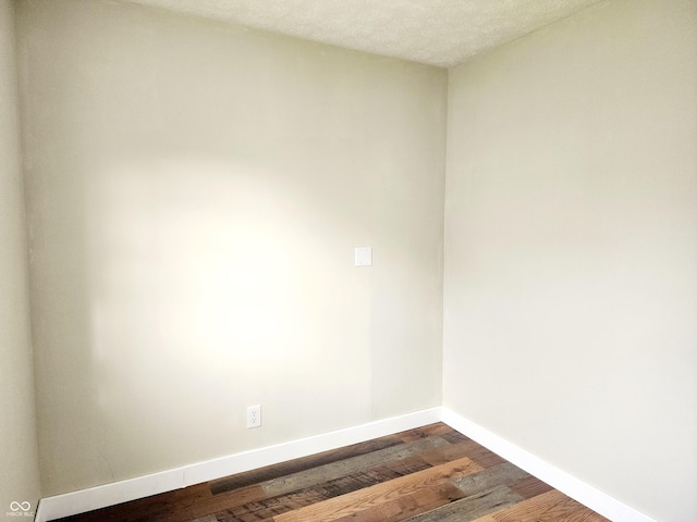 unfurnished room with dark hardwood / wood-style floors and a textured ceiling